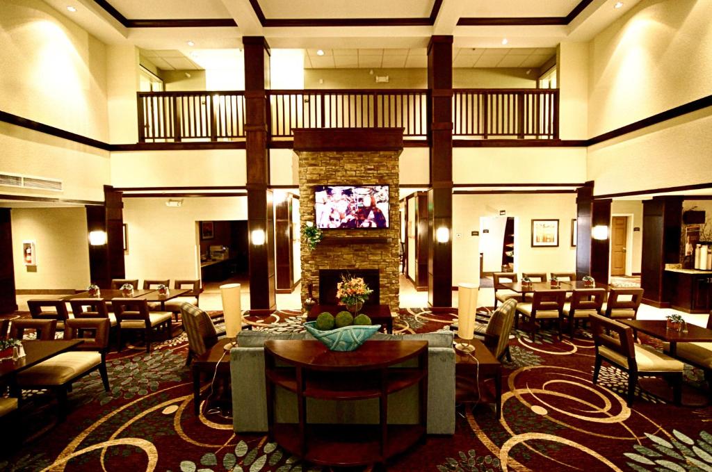 eine Hotellobby mit einem Kamin sowie Tischen und Stühlen in der Unterkunft Staybridge Suites Minot, an IHG Hotel in Minot