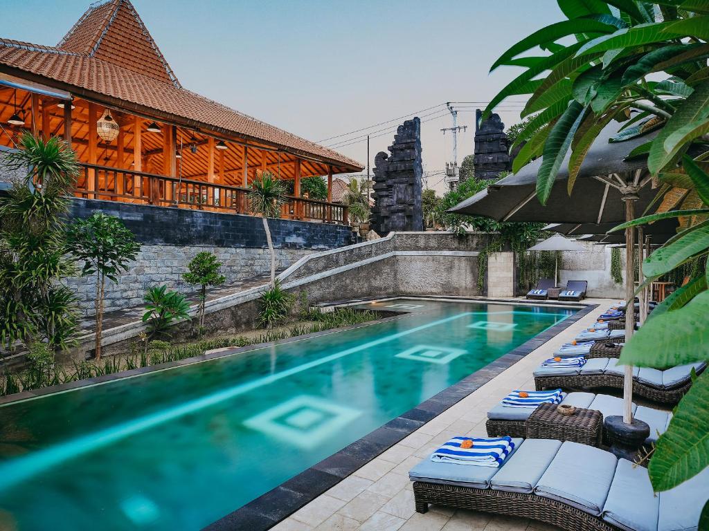 a swimming pool with lounge chairs next to a building at Bale Gede Lembongan in Nusa Lembongan