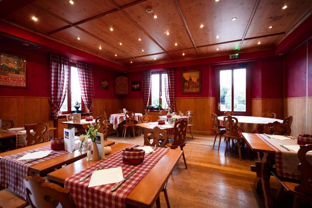 Le Rosenmeer - Hotel Restaurant, au coeur de la route des vins d'Alsace في Rosheim: مطعم به طاولات وكراسي وجدران حمراء