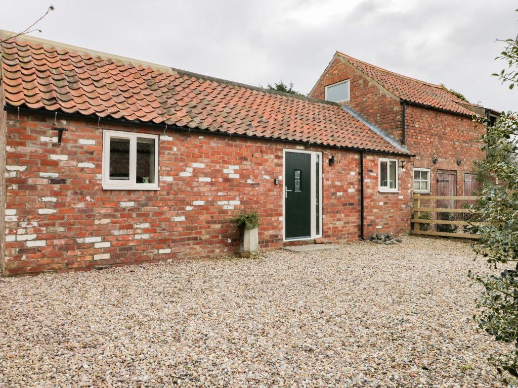 a brick house with a gravel driveway in front of it at Robin's Nest Cottage in Great Driffield