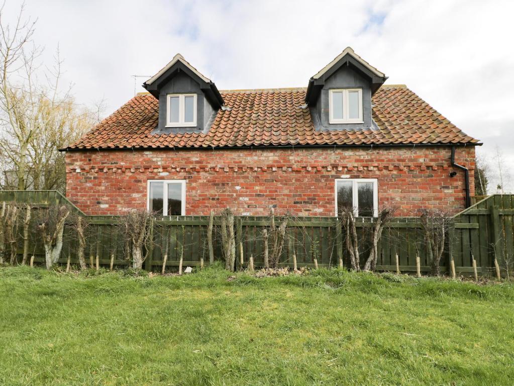 una casa de ladrillo con una valla delante de ella en Pipistrelle Cottage, en Great Driffield