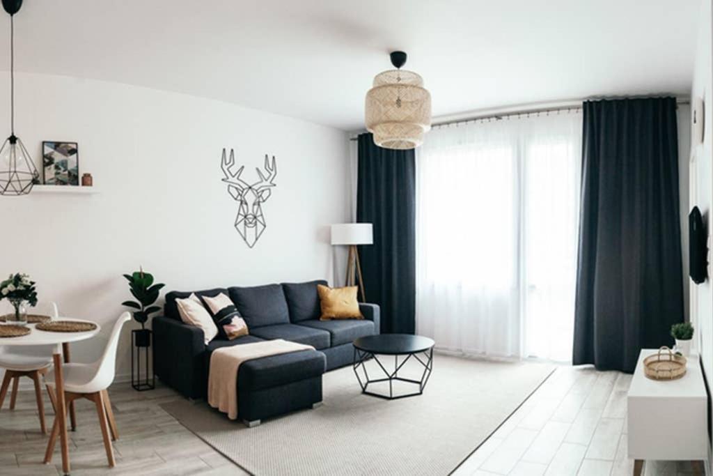 a living room with a blue couch and a table at Hello Apartments RAI Rajska in Gdańsk