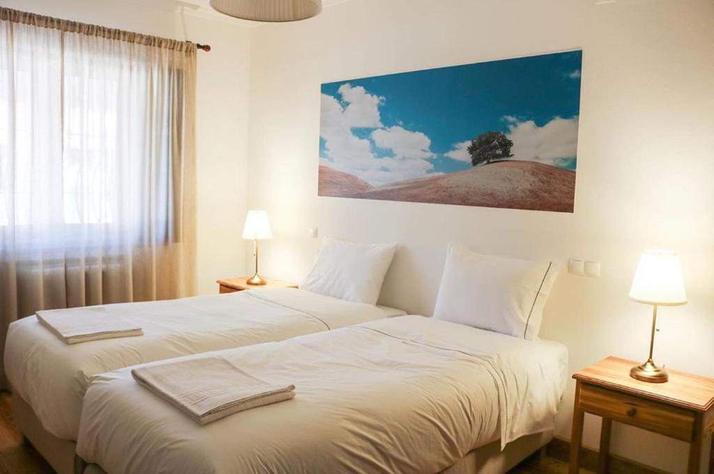 a bedroom with two beds and a large window at Monte da Floresta B&B in Ferreira do Alentejo