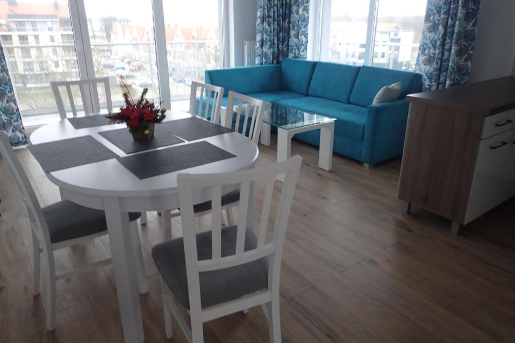 ein Wohnzimmer mit einem Tisch und einem blauen Sofa in der Unterkunft Ekskluzywny apartamet Pan Tadeusz III z widokiem na jezioro in Giżycko