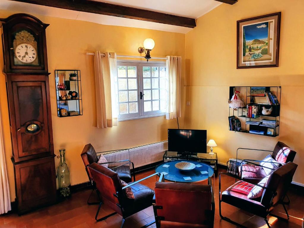 a living room with a table and chairs and a clock at Les Chambres d&#39;Hôtes du Cladan in LʼÉpine