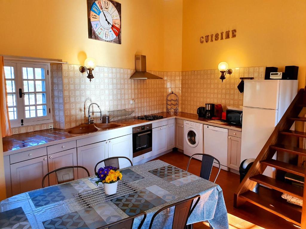 a kitchen with a table and a kitchen with a refrigerator at Les Chambres d&#39;Hôtes du Cladan in LʼÉpine