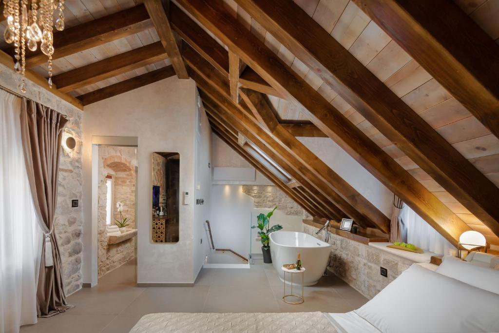 an attic bathroom with a tub and a sink at Luxury Rooms MA de Dominis in Split