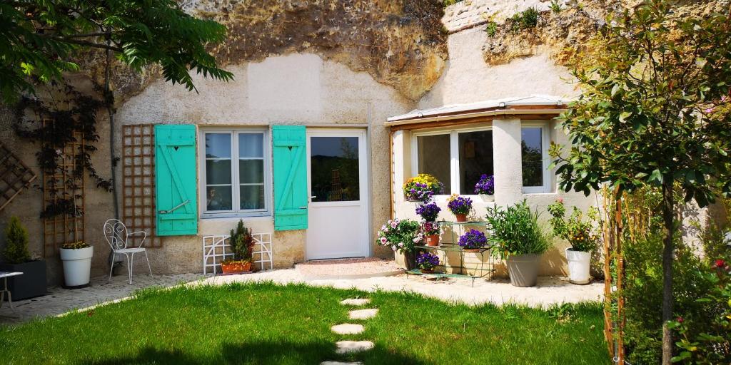 een huis met turquoise deuren en bloemen in de tuin bij Caves du Coteau 3 in Lunay