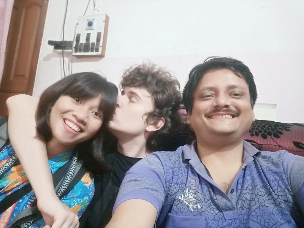 a group of three people sitting on a couch kissing at Green Home Stay Kolkata in Kolkata