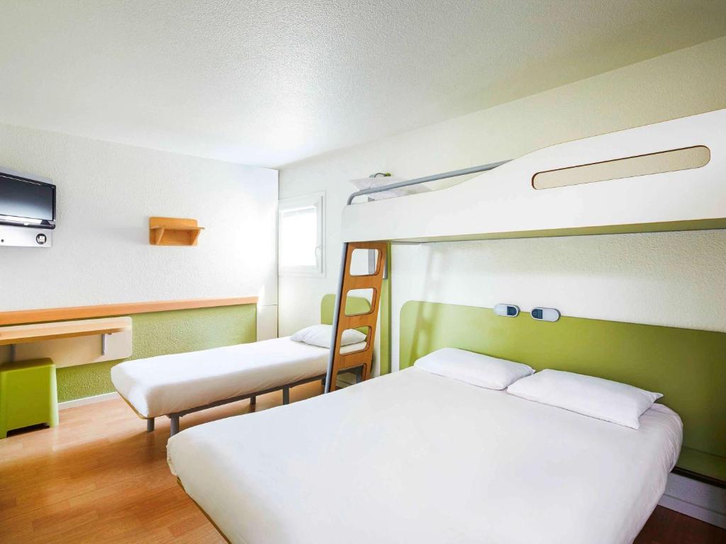 a bedroom with two bunk beds and a tv at ibis budget Chartres in Chartres
