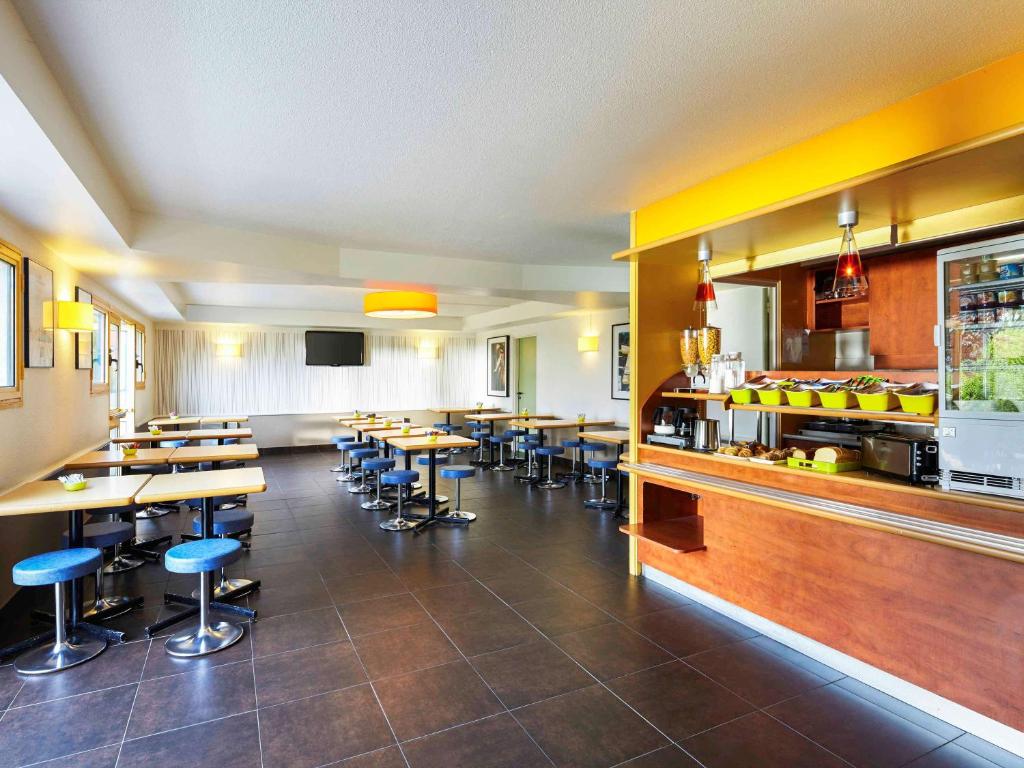 a restaurant with tables and chairs and a kitchen at ibis budget Chartres in Chartres