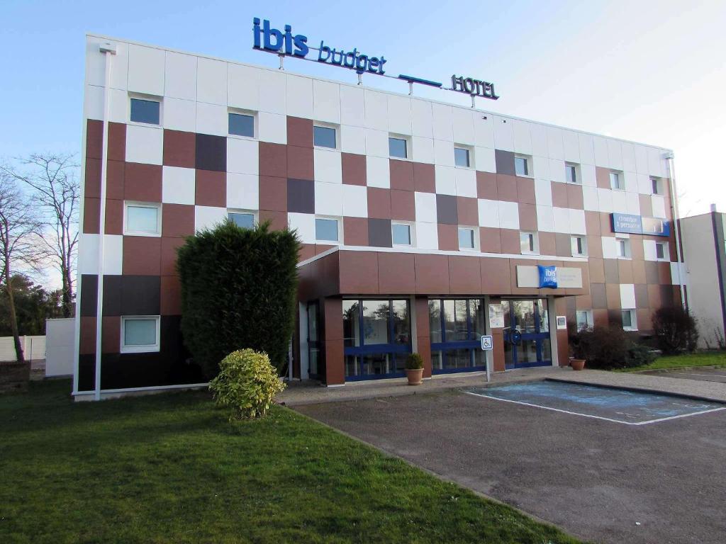 un grand bâtiment avec un panneau en haut dans l'établissement ibis budget Rouen Parc des Expos Zenith, à Saint-Étienne-du-Rouvray
