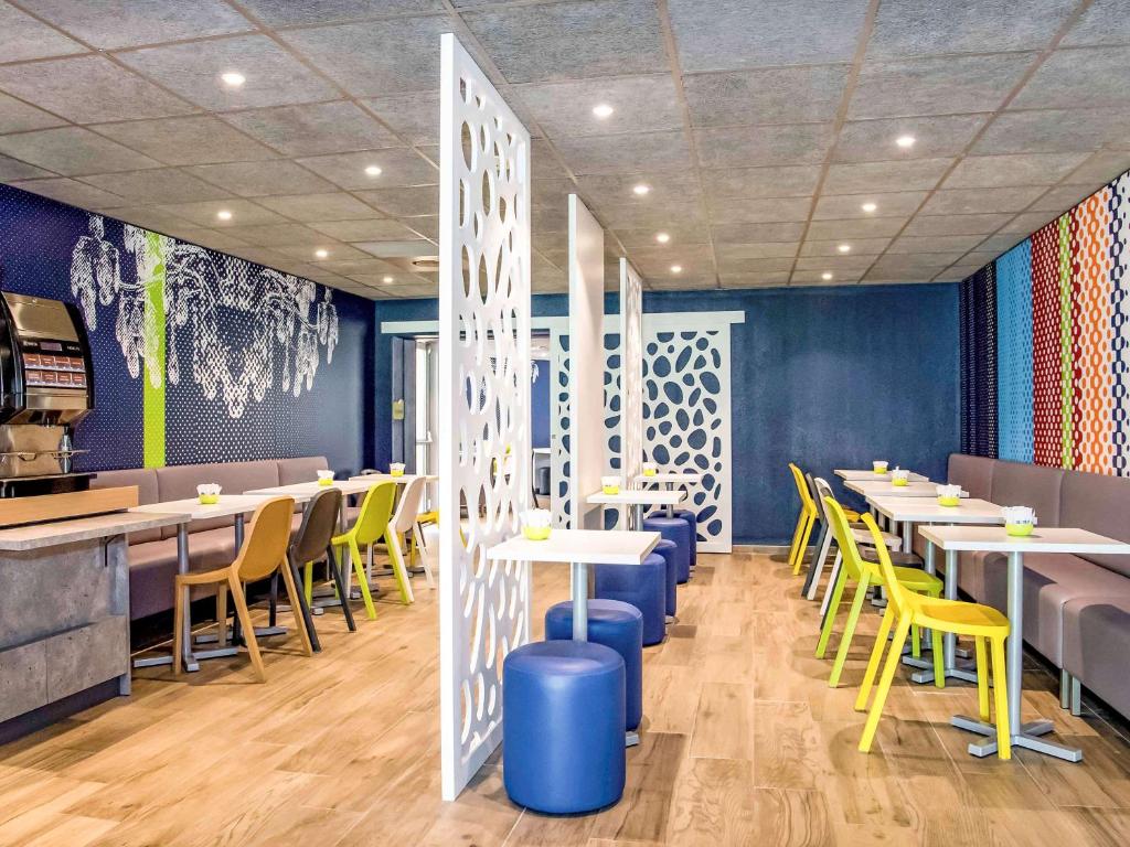 a dining room with tables and yellow chairs at ibis budget Avignon Centre in Avignon