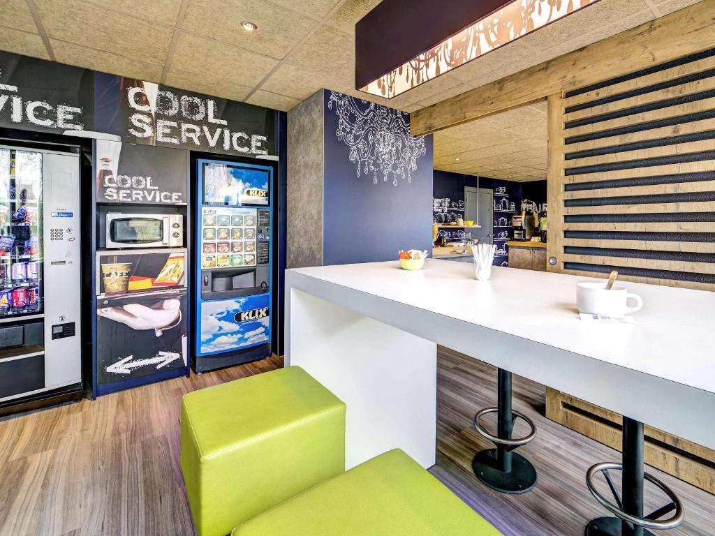 a fast food restaurant with a counter and a refrigerator at ibis budget Caen Mondeville in Mondeville