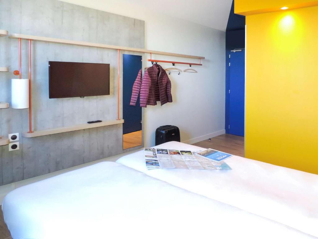 1 dormitorio con 1 cama y TV en la pared en ibis budget Fontainebleau Avon, en Avon