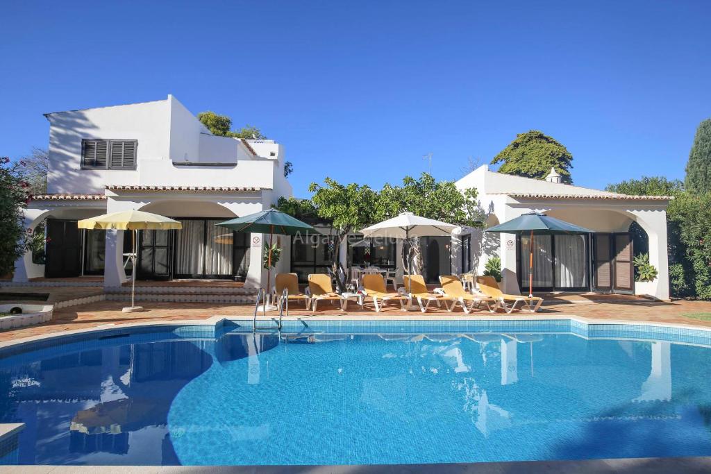 a swimming pool with chairs and umbrellas next to a house at Casa Carioca in Benagil