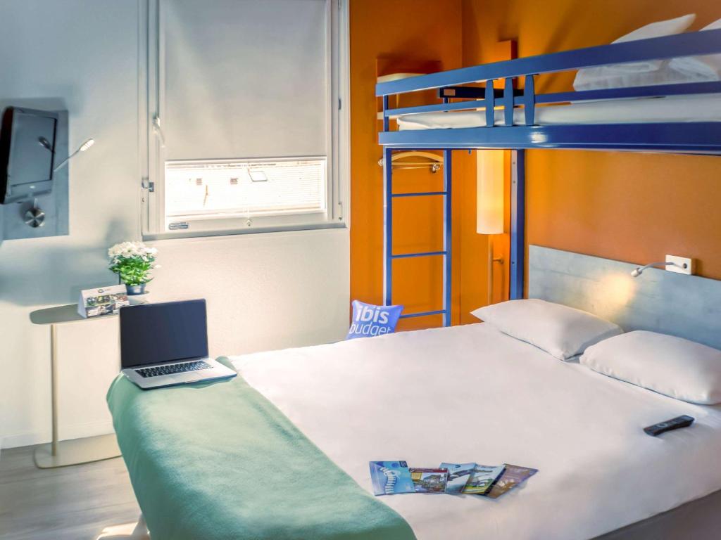 a bedroom with a bed with a laptop on it at ibis Budget Colmar Centre Gare in Colmar