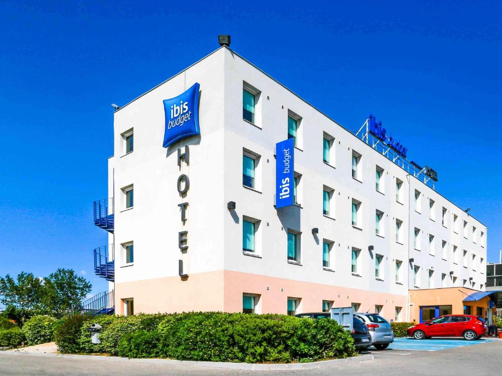 un grand bâtiment blanc avec des panneaux bleus. dans l'établissement ibis Budget Hotel Vitrolles, à Vitrolles