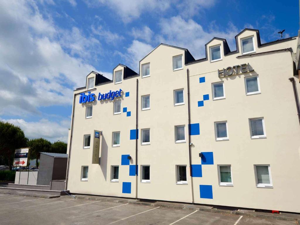 a large white building with blue squares on it at ibis budget Brive La Gaillarde in Brive-la-Gaillarde