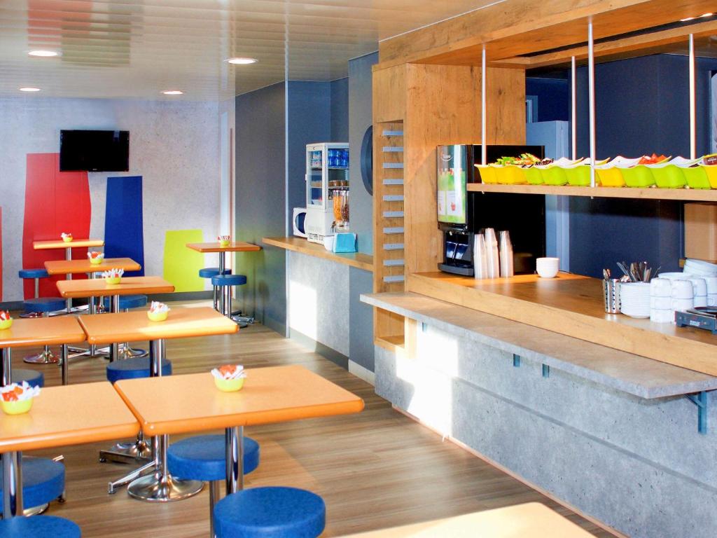 ein Restaurant mit Holztischen und blauen Stühlen in der Unterkunft ibis budget Flers Grands Champs in Flers