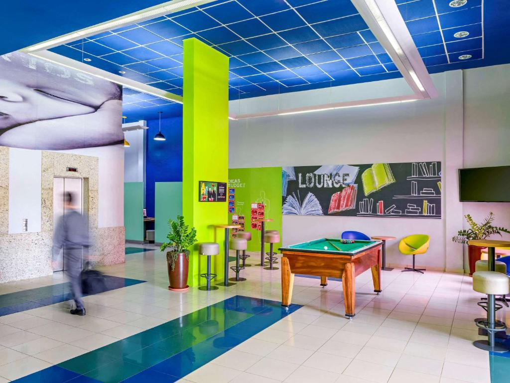 a man walking in a room with a pool table at ibis budget Belem in Belém