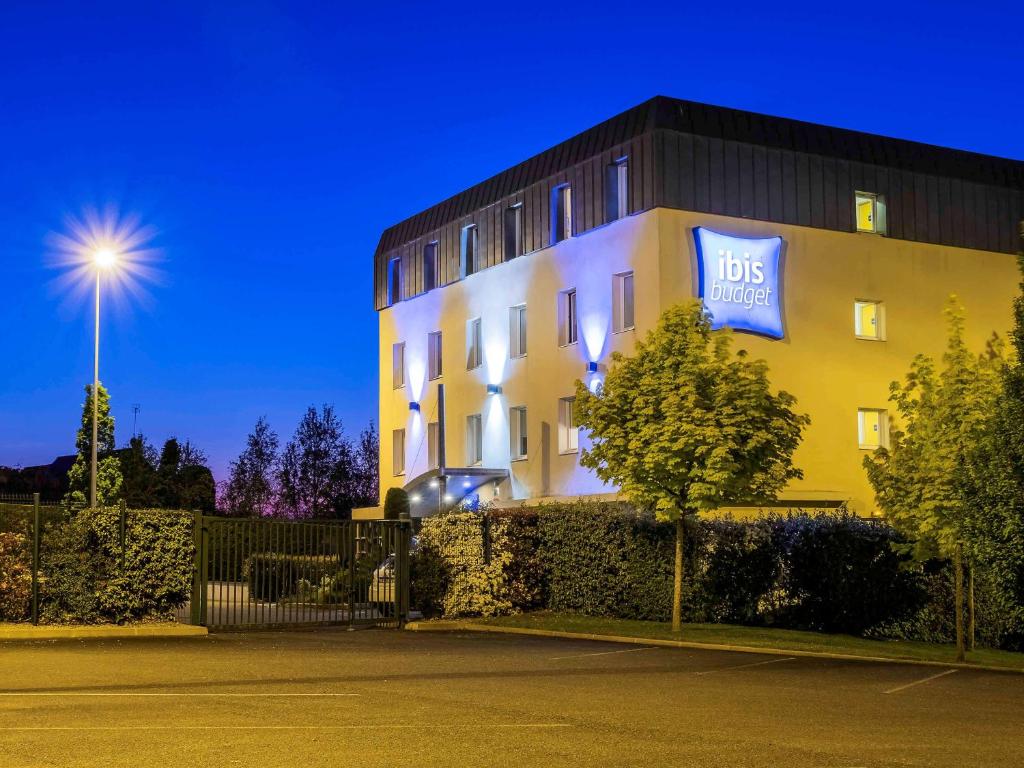 un grand bâtiment jaune avec un panneau bleu dans l'établissement ibis budget Amboise, à Amboise