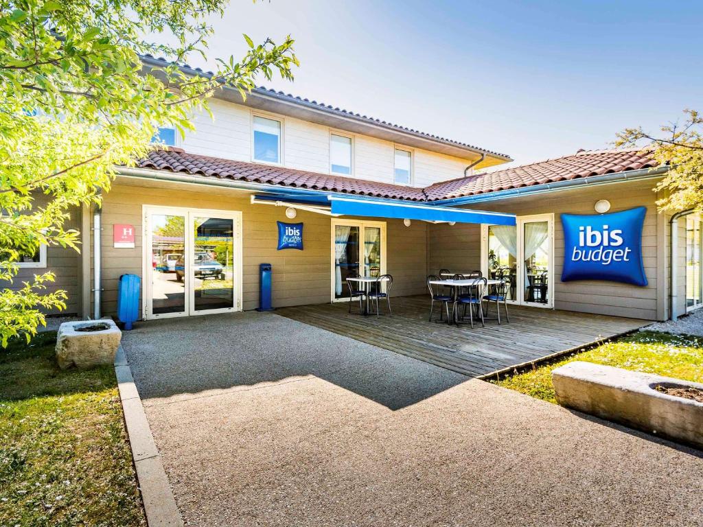 a building with a patio with a table and chairs at ibis budget Bourg en Bresse in Bourg-en-Bresse