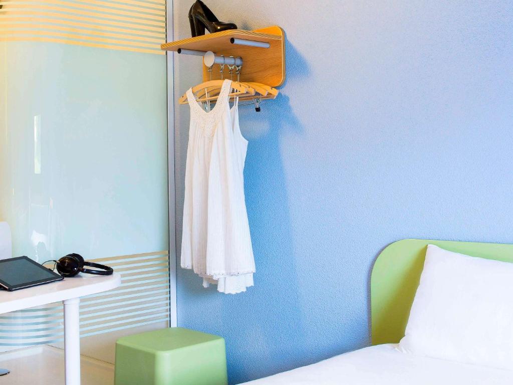 a bedroom with a white dress hanging on a blue wall at ibis budget Montceau les Mines in Montceau-les-Mines
