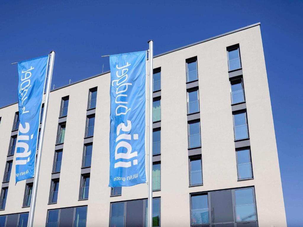 un edificio con dos banderas azules delante de él en ibis budget Konstanz en Konstanz