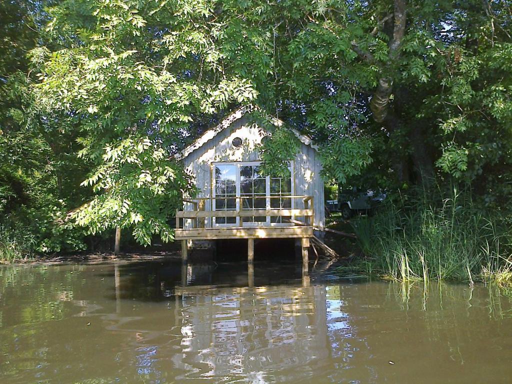 una casa en medio de un cuerpo de agua en La cabane sur l'eau, en Cul-des-Sarts