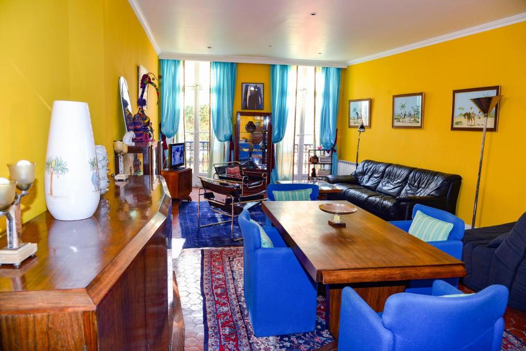 uma sala de estar com uma mesa de madeira e cadeiras azuis em Appartement Cannes em Cannes