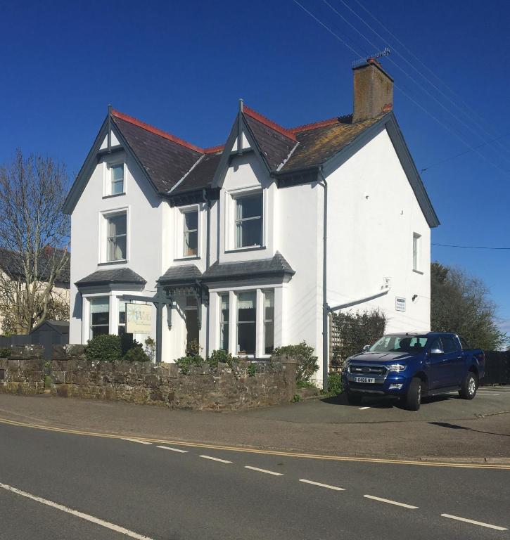 a white house with a car parked in front of it at The Wylfa in Abersoch