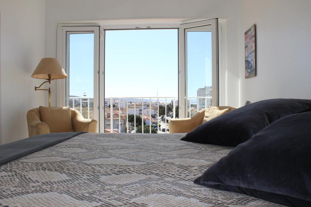 um quarto com uma cama grande e uma janela grande em Golden Loft Caparica em Costa da Caparica