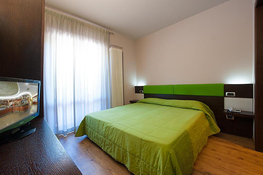 um quarto com uma cama verde e uma televisão de ecrã plano em Hotel Plestina Ristorante Pizzeria em Foligno