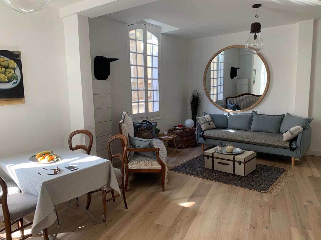 uma sala de estar com um sofá, uma mesa e um espelho em COSY CENTRE HISTORIQUE em Arles