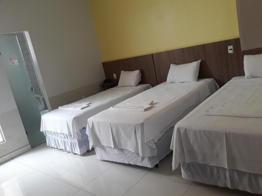 2 camas en una habitación de hotel con sábanas blancas en Big Hotel, en Imperatriz