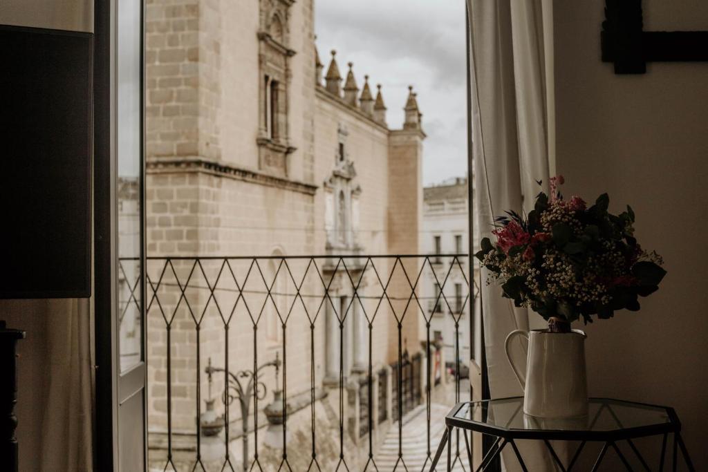 Casa da Catedral Ramona في بطليوس: إناء من الزهور على طاولة أمام النافذة