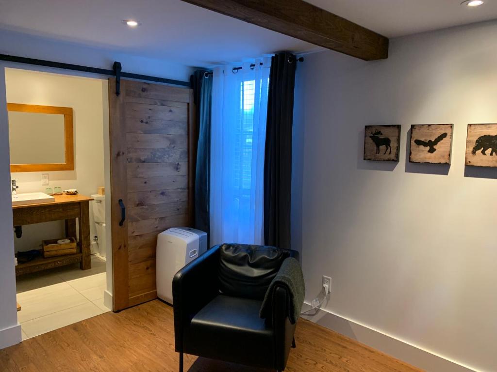 a living room with a black chair and a window at Restaurant et Gite Les Passionnés in Val-David