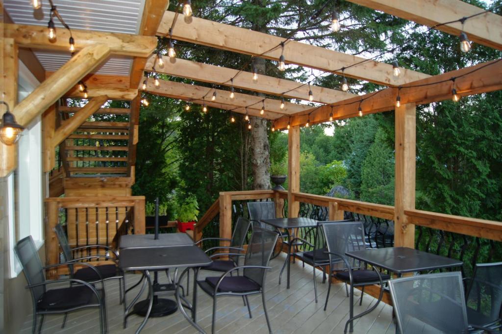a patio with tables and chairs under a wooden pergola at Restaurant et Gite Les Passionnés in Val-David
