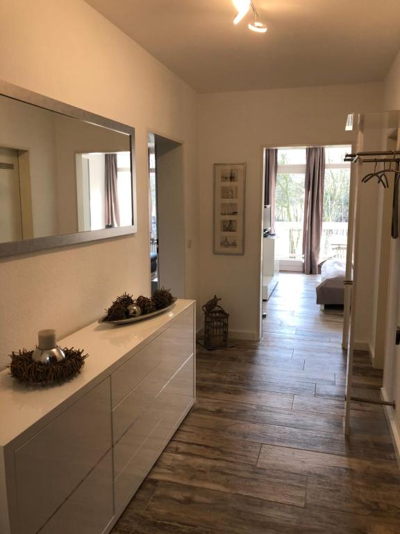 ein Badezimmer mit einem großen Spiegel und Holzboden in der Unterkunft Moderne Ferienwohnung am Yachthafen Bad Zwischenahn in Bad Zwischenahn