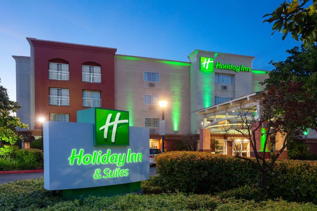 um hotel com uma placa em frente a um edifício em Holiday Inn & Suites San Mateo - SFO, an IHG Hotel em San Mateo