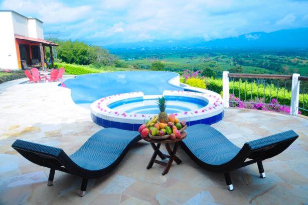 a patio with two chairs and a table with a bowl of fruit at Casa Mar Verde in Armenia