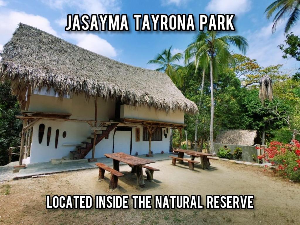 una cabaña con dos bancos delante de ella en Hotel Jasayma dentro del Parque Tayrona, en El Zaino