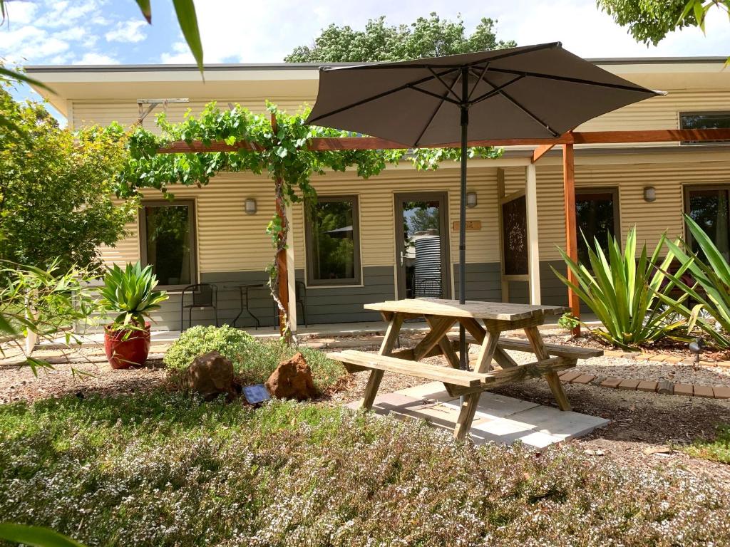 a picnic table with an umbrella in front of a house at The Grape and Olive at Willunga in Willunga