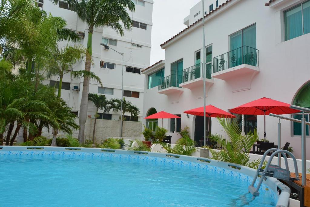 una piscina frente a un edificio con sombrillas rojas en Hotel Casablanca CHIPIPE, en Salinas