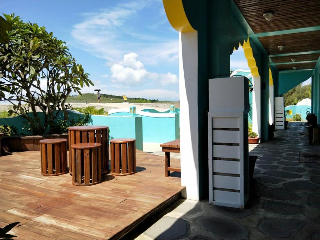 patio con 2 taburetes, nevera y piscina en The Domed Tile B&B, en Magong