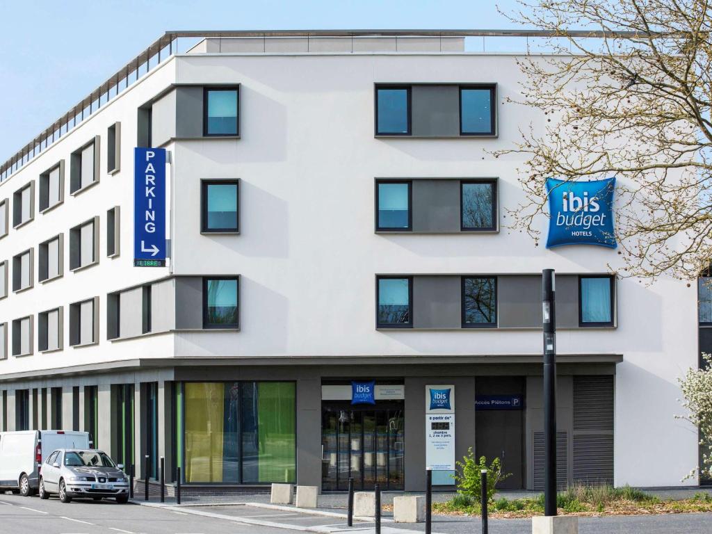 un bâtiment blanc avec un panneau indiquant un bloc de véhicules dans l'établissement ibis budget Saint Quentin Yvelines - Vélodrome, à Montigny-le-Bretonneux