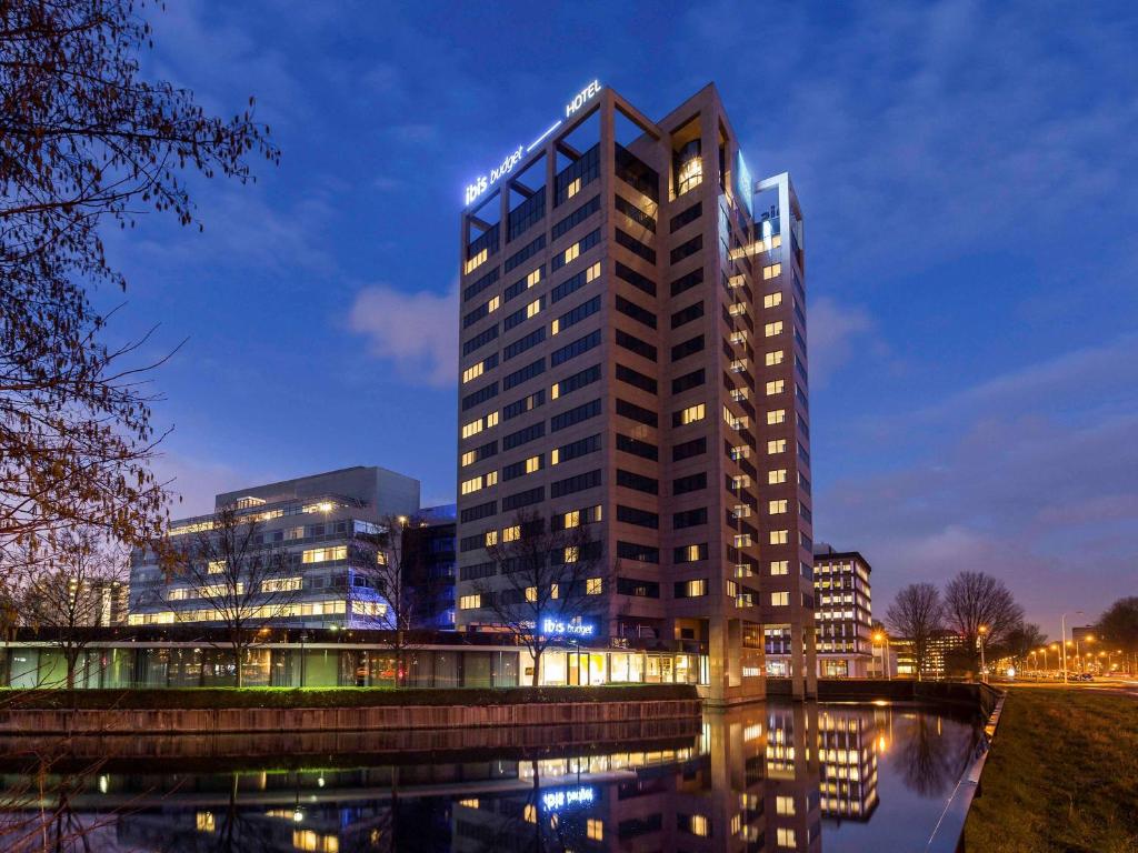 un edificio alto se ilumina por la noche en ibis budget Amsterdam City South, en Amstelveen