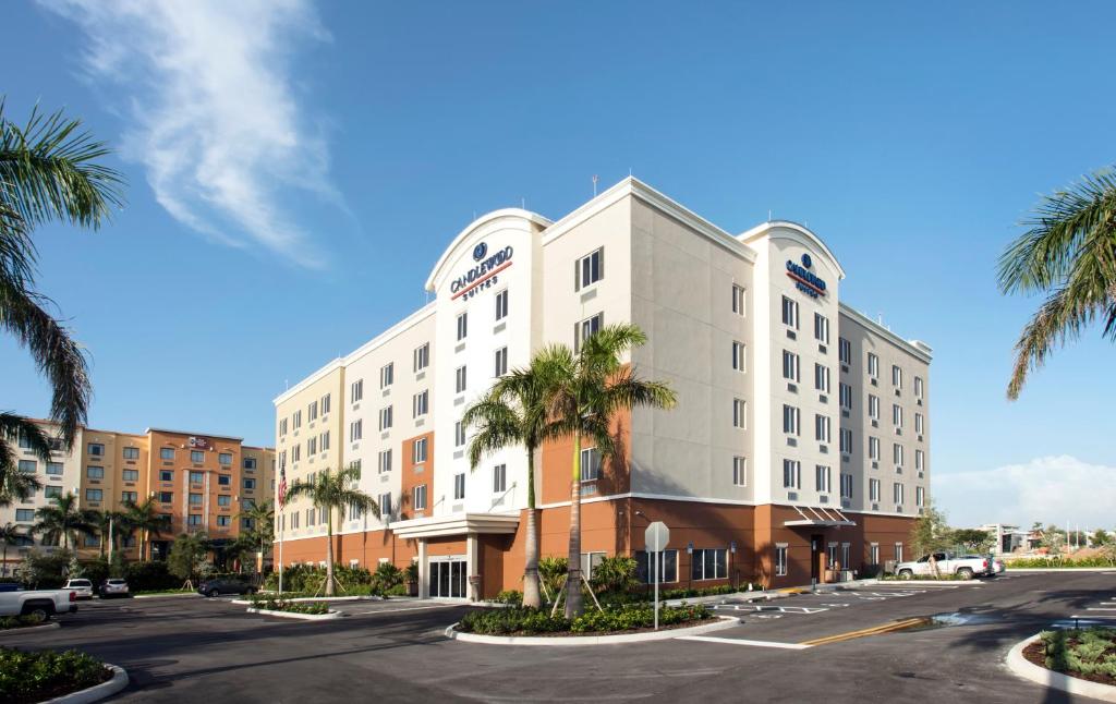 a hotel with palm trees in front of a street at Candlewood Suites - Miami Exec Airport - Kendall, an IHG Hotel in Kendall