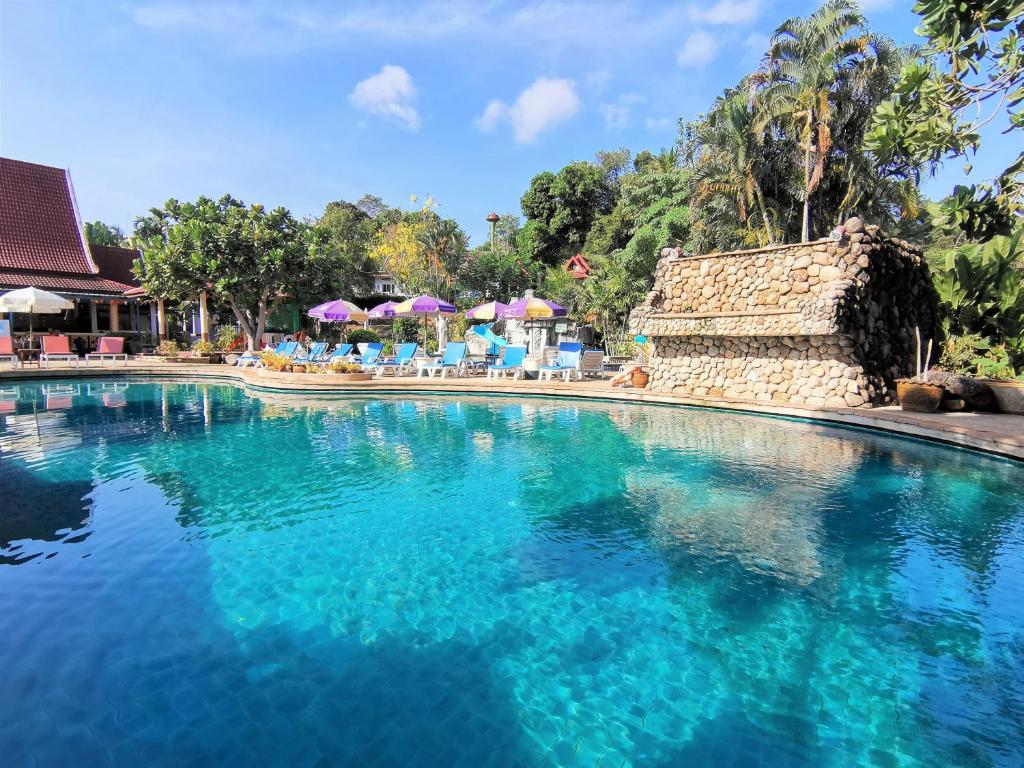 una piscina con agua azul, sillas y sombrillas en Holiday Villa, Lanta en Ko Lanta